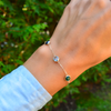 Close-up of woman's wrist wearing a personalized Grand 3 Birthstone bracelet featuring 6mm gemstones on a 1.17mm cable chain.