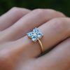 Woman with a Greenwich ring featuring four 4 mm round Nantucket blue topaz and one 2.1 mm diamond prong set in 14k gold