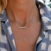 Woman wearing a Rosecliff Bar necklace featuring eleven alternating sustainably grown 2mm diamonds and alexandrite gemstones.