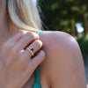 Woman wearing two rings including a Greenwich ring featuring one 4 mm garnet and one 2.1 mm diamond prong set in 14k gold