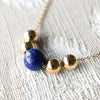 Bristol Bead necklace featuring an 8mm lapis lazuli bead & four 6mm gold beads, two on either side, on a 1.17mm cable chain.
