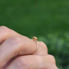 Hand wearing a 1.6 mm wide 14k yellow gold Grand ring featuring one 6 mm briolette cut bezel set citrine