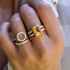 Woman's hand wearing multiple rings including a Warren ring in 14k gold with accent diamonds featuring one 10 x 8 mm citrine