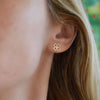 Woman wearing Clover Stud Earrings in 14k yellow gold bringing good luck, featuring 9.1mm cutout clover.