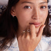 Woman wearing assorted rings, including a Personalized Rosecliff Small Circle Birthstone Ring in 14k gold featuring a sparkly open circle with genuine gemstones in customizable patterns