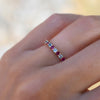 Woman's hand wearing a personalized Rosecliff Stackable ring with eleven 2mm Nantucket blue topaz and Ruby gemstones.