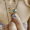 A woman showcases a collection of Warren rings in 14k yellow gold, each adorned with a vertically placed, bezel-set emerald-cut gemstone measuring 10 x 8 mm.