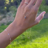 Woman holding a Greenwich cable chain necklace featuring one 4 mm sapphire and one 2.1 mm diamond bezel set in 14k gold