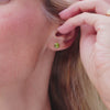 Woman wearing a pair of 14k yellow gold Grand stud earrings each featuring one 6 mm briolette cut peridot