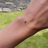 Woman wearing a Classic cable chain bracelet featuring one 4 mm briolette cut garnet bezel set in 14k gold