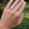 Woman wearing two rings including a 1.6 mm wide 14k gold Grand ring featuring one 6 mm briolette cut bezel set turquoise