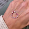 Woman holding a Rosecliff Heart Necklace featuring twenty alternating rubies and diamonds prong set in 14k yellow Gold