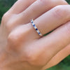 Hand with a Rosecliff stackable ring featuring eleven alternating 2mm round cut sapphires and diamonds prong set in 14k gold