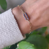 Woman wearing a 14k yellow gold Adelaide paperclip chain pavé bracelet featuring one sapphire-encrusted link