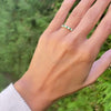 Woman's hand with a Rosecliff stackable ring featuring eleven alternating 2mm emeralds and diamonds prong set in 14k gold