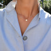 Woman wearing a 14k yellow gold Classic necklace featuring two birthstones and one 1/4” flat disc engraved with the letter H