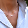 Woman with a 14k yellow gold Classic necklace featuring six birthstones and one 1/4” flat disc engraved with the letter H