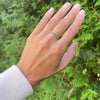 Female hand with a Rosecliff stackable ring featuring eleven 2 mm faceted round cut emeralds prong set in 14k yellow gold
