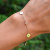 Woman with a 14k yellow gold Classic bracelet featuring birthstones and two 1/4” flat discs engraved with letters A & H