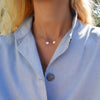 Woman wearing a 14k yellow gold cable chain necklace featuring two 1/4” flat discs engraved with the letters L and R