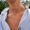 Woman wearing a 14k gold Classic necklace featuring 3 birthstones and three 1/4” flat letter-engraved discs