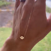 Woman holding a 14k yellow gold 1.17 mm cable chain Noel necklace featuring one 1/4” flat disc engraved with a snowflake