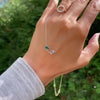 Woman holding a Grand 14k yellow gold 1.17 mm cable chain necklace featuring two 6 mm briolette cut bezel set gemstones