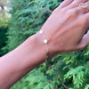 Woman's hand wearing a 14k yellow gold cable chain bracelet featuring 1/4” flat discs engraved with letters