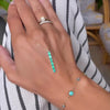 Woman's hand wearing assorted jewelry and holding a Providence 6 Emerald Pendant set in 14k yellow gold