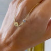 Woman holding a 14k yellow gold Classic necklace featuring one birthstone and one 1/4” flat disc engraved with the letter J