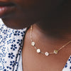 Woman wearing a 14k yellow gold cable chain necklace featuring four 1/4” flat engraved letter discs, spelling Vote