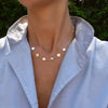Woman wearing a 14k yellow gold cable chain necklace featuring six 1/4” flat engraved letter discs, spelling Vivian