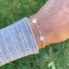 Woman with a Newport 14k gold bracelet featuring 4 mm gemstones and two 1/4” flat discs engraved with the letters H and L
