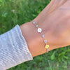 Woman wearing a Newport gold bracelet featuring 4 mm gemstones and three 1/4” flat discs engraved with the letters C, M & R