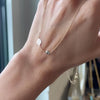 Woman holding a 14k gold Solidarity necklace featuring one birthstone and one 1/4” flat disc engraved with a sunflower