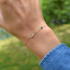 Woman's hand with a 1 Grand 1 Classic bracelet in 14k gold featuring one 4 mm and one 6 mm briolette cut bezel set gemstone