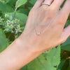 Woman holding a Grand 14k yellow gold 1.17 mm cable chain necklace featuring one 6 mm briolette cut bezel set white topaz