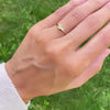 Woman wearing a Greenwich ring featuring one 4 mm faceted round cut gemstone and one 2.1 mm diamond prong set in 14k gold