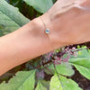 Woman wearing a Grand 1.17 mm cable chain bracelet in 14k gold featuring one 6 mm briolette cut Nantucket blue topaz