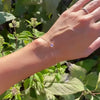 Woman wearing a Grand 1.17 mm cable chain bracelet in 14k yellow gold featuring one 6 mm briolette cut bezel set moonstone