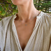 Woman wearing a Grand & Classic necklace featuring one 6 mm and four 4 mm Aquamarines bezel set in 14k yellow gold