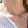 Woman wearing a Bayberry 11 Birthstone necklace featuring 4 mm briolette rubies bezel set in sterling silver