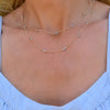 Woman wearing a Bayberry Birthstone Wrap necklace featuring 4 mm briolette cut aquamarines bezel set in 14k yellow gold