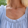 Woman wearing a Bayberry Birthstone Wrap necklace featuring 4 mm briolette cut Nantucket blue topaz bezel set in 14k gold