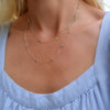 Woman wearing a Bayberry Birthstone Wrap necklace featuring 4 mm briolette cut peridots bezel set in 14k yellow gold