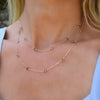 Woman with a Bayberry Birthstone Wrap necklace featuring 4 mm briolette cut pink tourmalines bezel set in 14k yellow gold