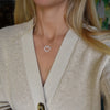 Woman wearing a Rosecliff Heart Necklace featuring twenty faceted round cut aquamarines prong set in 14k yellow Gold