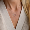 Woman with a Rosecliff Heart Necklace featuring twenty faceted round cut white topaz prong set in 14k yellow Gold