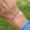 Woman wearing a 1 Grand 1 Classic bracelet in 14k gold featuring one 4 mm and one 6 mm briolette cut bezel set gemstone