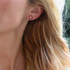 Woman wearing a 14k yellow gold Greenwich 5 Birthstone earring featuring five 4 mm garnets and one 2.1 mm diamond